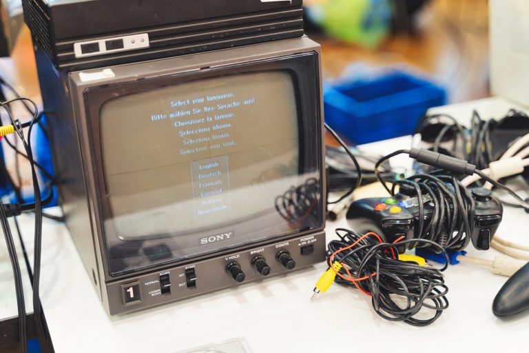 Ein alter Bildschirm, neben dem mehrere Controller liegen.